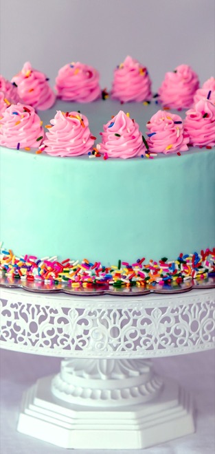 A custom-decorated layer cake on a display stand, cropped for a mobile screen