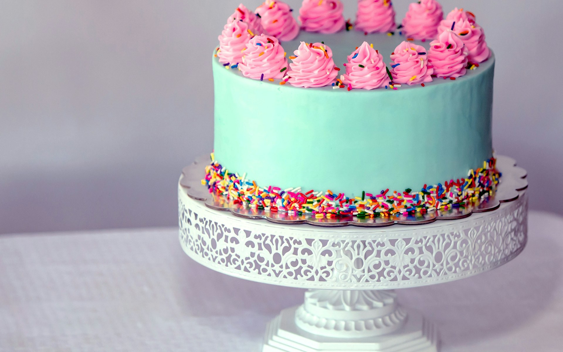 A custom-decorated layer cake on a display stand, styled as a bakery website hero